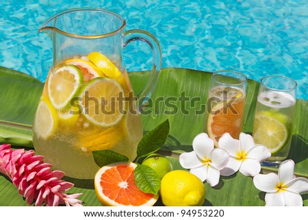Two glasses and Jug of home made iced lemonade  on edge of swimming pool.