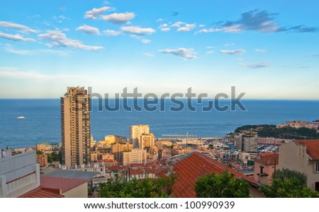 Picture of sunset at the resort area of Monaco. The main object is the high tower of hotel against the backdrop of the sea horizon.