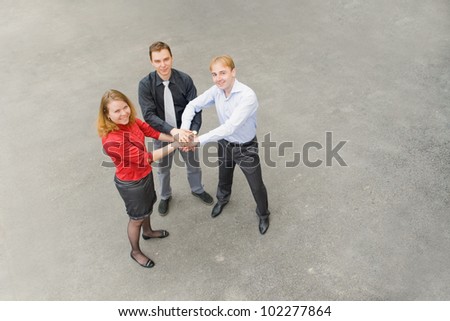 Image of business team of 3 people who have developed the ultimate strategy for further action. Focus is made on top of the gray background of the empty street.