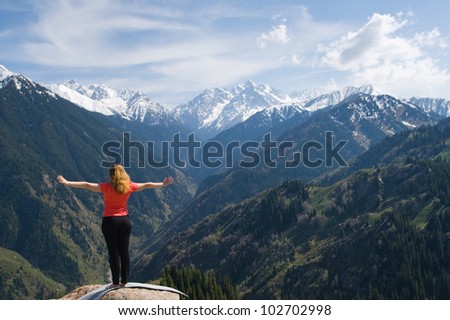 The young woman is doing a yoga asana Ã?Â¢??Sun SalutionÃ?Â¢?Ã?Â� on the summit. On the background is a range of high tops of mountains.