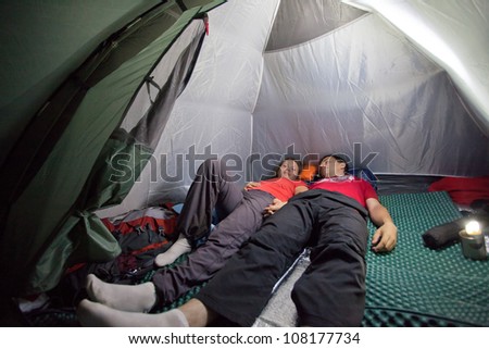 Image of sleeping tourists inside the tent camp on the background of night lighting flashlight in Almaty, Kazakhstan