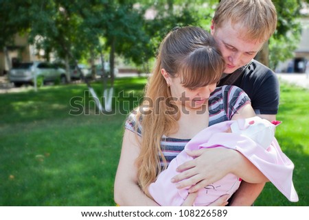 Image of young parents holding the hands of his first child - a girl on a sunny summer day. Almaty.