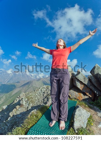 Image of a young girl who does yoga - Sun Salutation pose on top. In the background the snowy mountain tops of the clouds. Tibet and the Himalayas.