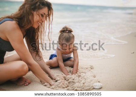 Children\'s Day. Mom and happy baby playing near the beach. Traveling with your family, child. Games with child affect early development. Important to spend enough time with your kids.