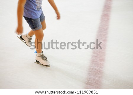 Image of people who are ice skating in the ice rink indoors.