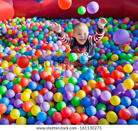 little children on the background of many multicolored small balls
