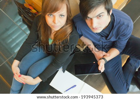 male and female university students sitting on a bench and do their homework