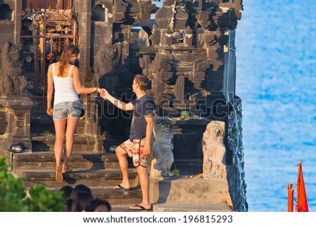 girl and young man by the hand up the stairs to the temple. Indonesia, Bali
