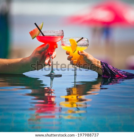 Orange and watermelon cocktail in hand with cocktail straw on bright background