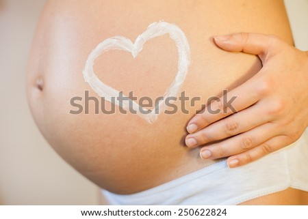 Pregnant woman with concept of love, heart applied as a stretch mark cream