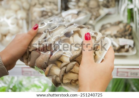 Image of packaged mushrooms with woman hand in the supermarket