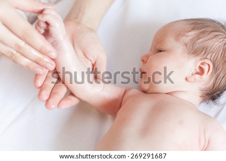 Mother makes newborn baby massage, apply oil on the hand, with white background