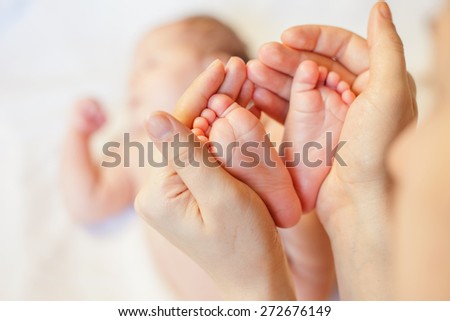 Mother holding baby feet, there is concept or idea of love, family and happiness at the home, like mother caring for newborn