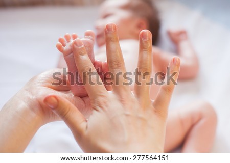 Mother makes massage for happy baby, apply oil on the foot, with white background