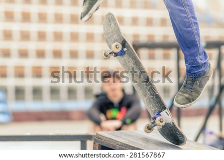 close-up image of teenager doing a trick by skateboard on a rail in the skate park outdoors