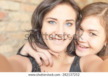 Two happy and funny girls make selfie on camera or mobile phone. They are now a party or birthday, and celebrate fun!