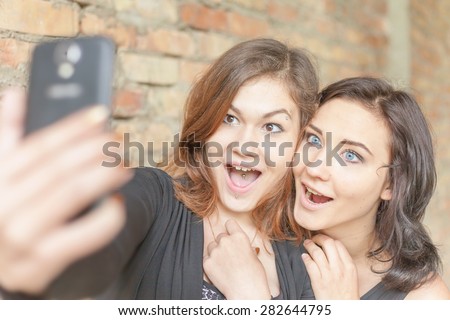Two happy and funny girls make selfie on mobile phone. They are now a party or birthday, and celebrate fun!