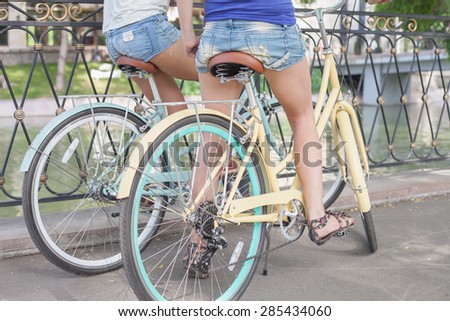closeup beautiful sexy women dressed in short shorts travel by city vintage bicycle at summer time