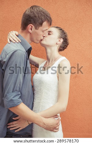 Kissing young couple at red wall background. Image ready for International, World Kissing Day 6 July or Valentine\'s Day, with copy space for any text or design