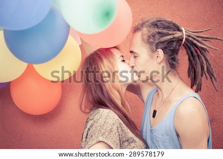 Happy, funny young couple kissing at background of color balloons. Celebrate a birthday holiday! Ready for International, World Kissing Day 6 July, Valentine\'s Day, copy space for any text, design