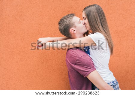 Happy and funny couple kissing at red wall background. Image ready for International, World Kissing Day 6 July or Valentine\'s Day, with copy space for any text or design