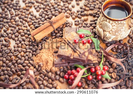Background of chocolate bar, a cup of coffee, cinnamon sticks, hazelnuts, cranberries and coffee beans scattered on the wooden table. Day chocolate and coffee daily. Brugge - Belgian chocolate capital