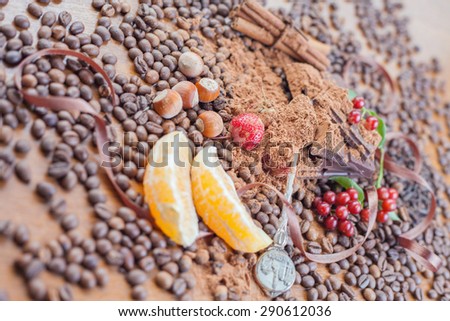Background of chocolate bar, orange slice, cinnamon sticks, hazelnuts, strawberries and coffee beans scattered on wooden table. Day chocolate. Brugge - Belgian chocolate capital