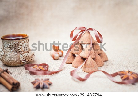 Chocolate truffles candies and vintage glass of milk or cream on background of burlap bag texture with anise flowers, hazelnuts and decorative ribbon, selective focus and old style for chocolate day