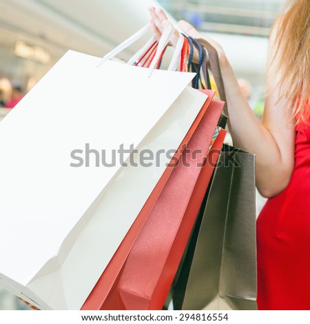 Closeup big bags fashion woman holding at shopping center, she dressed in red dress. There is a large copy space for text, label and design