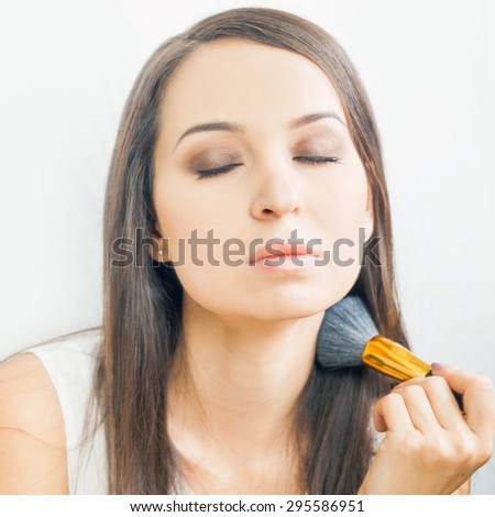 beautiful caucasian woman or makeup artist doing make up yourself using cosmetic brush for face at beauty salon with white background