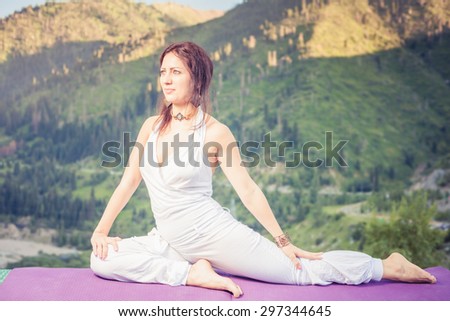 Young caucasian woman doing yoga at mountain, dressed in white sportswear. She relaxing and meditating at top of summit at yoga mat. Kazakhstan, Almaty, Medeo