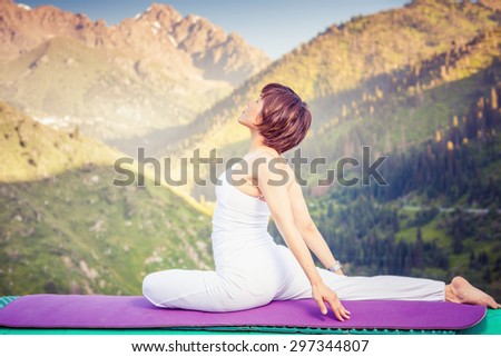Young asian woman doing yoga at mountain, dressed in white sportswear. She relaxing and meditating at top of summit at yoga mat. Kazakhstan, Almaty, Medeo