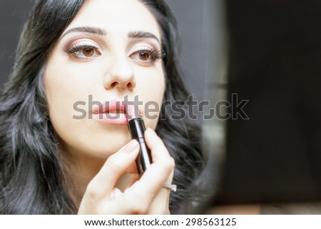 makeup artist woman doing make-up using cosmetic brush and mirror applying eye shadow on the eyelids for yourself at beauty salon with white background