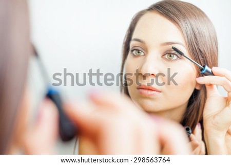 makeup artist woman doing make-up using cosmetic brush applying eye shadow on the eyelids for yourself at beauty salon with white background