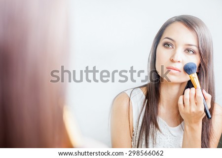 makeup artist woman doing make-up using cosmetic brush applying shadow cream on face for yourself at beauty salon with white background