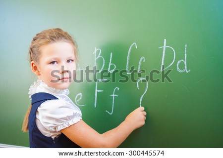 Schoolgirl wrote in chalk on blackboard and teach English language. The first lesson at the first of September began with the alphabet