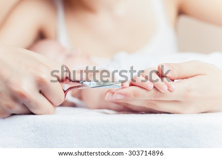 Mom tonsured nails on the hands newborn using nail scissors. Mother care is most important for baby healthy life