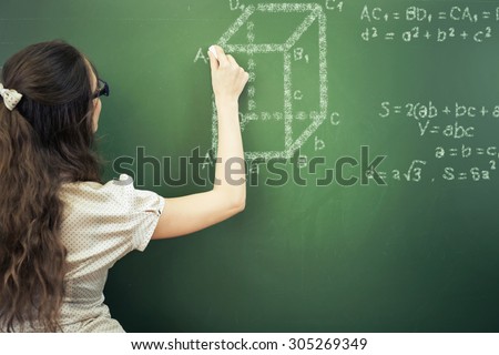 Smart student or teacher drawing mathematic formula at blackboard, dressed in university uniform and sunglasses, scribbled with chalk - formulas and drawing. Concept of intelligent and scientist woman