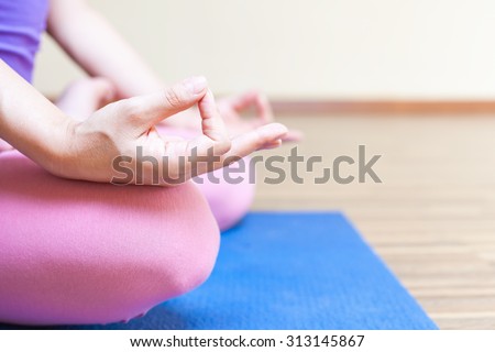 Unrecognizable person meditating and doing yoga exercise indoor. Sits in lotus position and feel harmony. Healthy lifestyles concept of body and soul