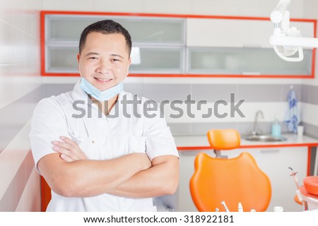 Happy and confident dentist doctor at stomatological clinic with modern high-tech furniture design and professional instruments