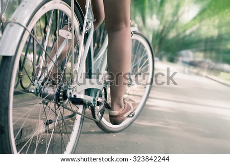 closeup of woman riding by blue vintage city bicycle at the city center with motion blur effect. It is like concept for activity and healthy lifestyle and environmentally friendly transport