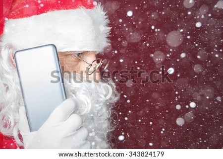 Santa Claus using a mobile phone at Christmas time. Santa calls to Elf or Dwarf. New Year. Snowy winter blizzard with magical snow and snowflakes. Copy space for design, text