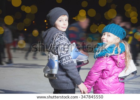 Happy children ice skating at ice rink outdoor, at winter night, sport and healthy lifestyle, ice skating at Holland. Funny kids, boy and girl, sister and brother. Family