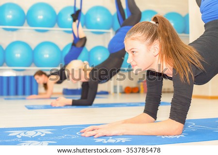 Young women doing aerial yoga exercise or antigravity yoga indoor. Fitness, stretch, balance, exercise and healthy lifestyle people. Woman using hammock.