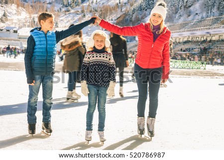 Happy family outdoor ice skating at rink. Winter activities