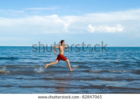 Running man on sea or beach in motion with spray of water / Running man on sea