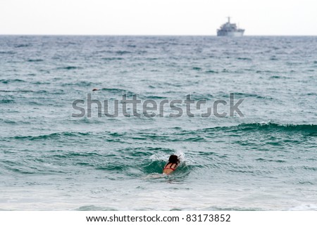 Swimming women in the sea. There is military ship on the foreground.