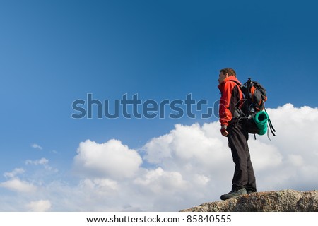 Climbing young adult at the top of summit with aerial view of the blue sky