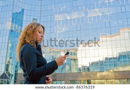 Young attractive businesswoman talking on mobile phone opposite office building