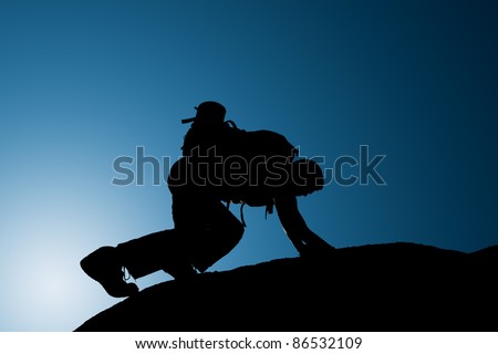 Silhouette of climbing young adult at the top of summit with aerial view of the blue sky